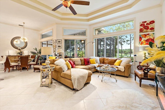 tiled living room with ceiling fan with notable chandelier, a raised ceiling, and crown molding