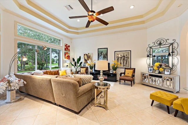 living room featuring light tile patterned floors, a tray ceiling, and crown molding