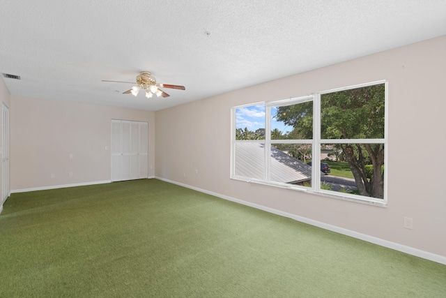 empty room with carpet flooring, ceiling fan, and a textured ceiling