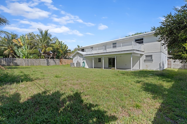 rear view of house featuring a lawn and a balcony