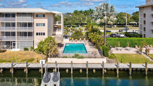 view of swimming pool with a boat dock, a patio area, and a water view