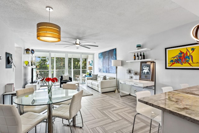 dining area with a textured ceiling, ceiling fan, and light parquet flooring