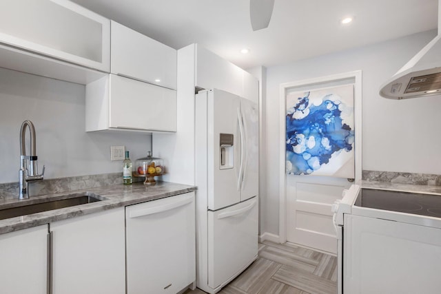 kitchen with light stone countertops, sink, white appliances, and white cabinets