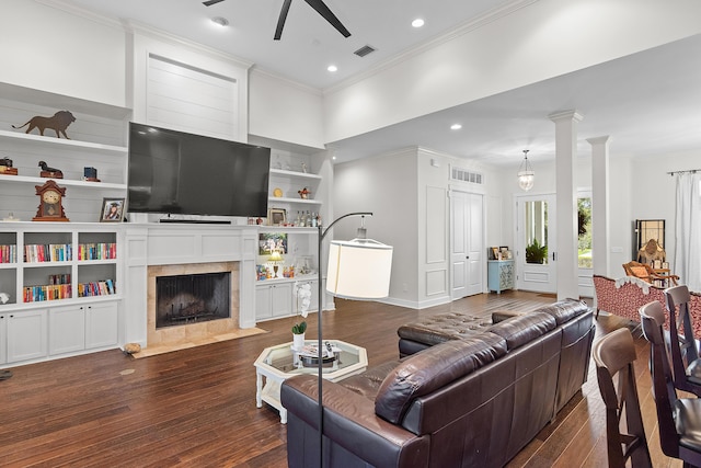 living room featuring ceiling fan, dark hardwood / wood-style flooring, crown molding, and a tiled fireplace