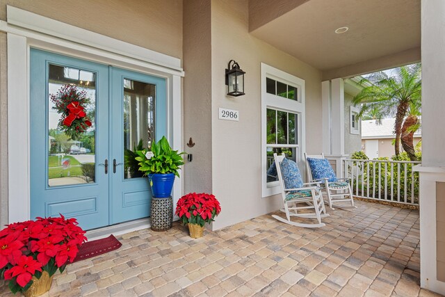 doorway to property featuring covered porch and french doors