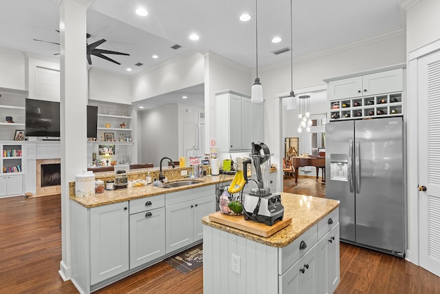 kitchen with kitchen peninsula, sink, pendant lighting, white cabinets, and built in refrigerator