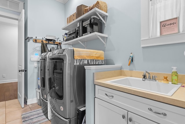 laundry area with sink, light tile patterned floors, cabinets, and independent washer and dryer