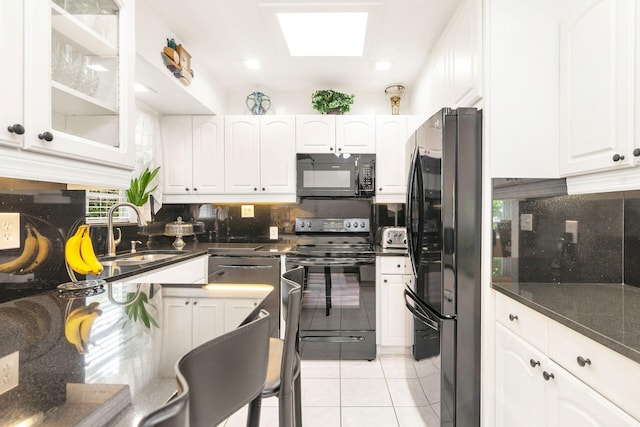 kitchen featuring backsplash, sink, black appliances, light tile patterned floors, and white cabinetry