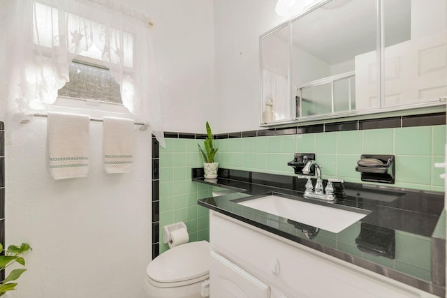 bathroom featuring vanity, toilet, decorative backsplash, and a shower with shower door