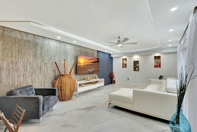 living room featuring a raised ceiling, ceiling fan, and wood walls