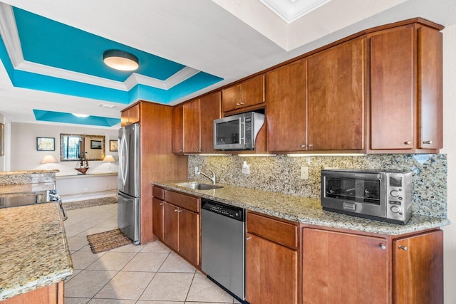 kitchen with light stone countertops, appliances with stainless steel finishes, a tray ceiling, and sink