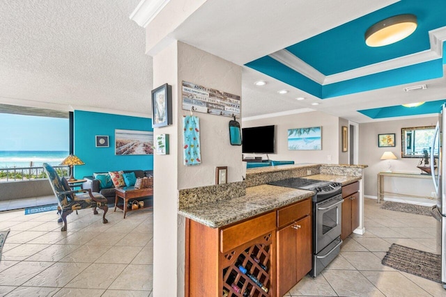 kitchen with light stone countertops, light tile patterned floors, crown molding, a textured ceiling, and stainless steel stove