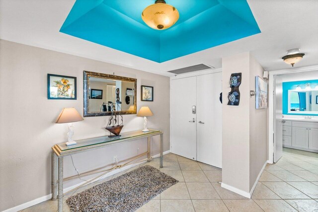 entrance foyer featuring a tray ceiling and light tile patterned flooring