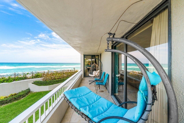 balcony featuring a view of the beach and a water view