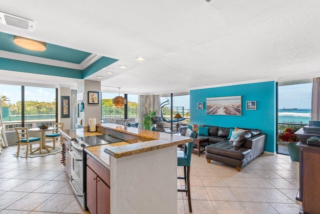 kitchen featuring light stone countertops, crown molding, stainless steel range with electric stovetop, a breakfast bar, and a water view