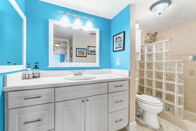 bathroom featuring a tile shower, vanity, and toilet