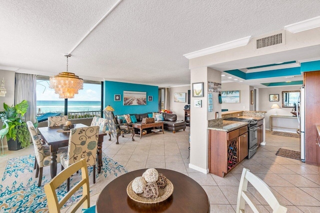 dining room with a water view, crown molding, light tile patterned floors, a textured ceiling, and a chandelier