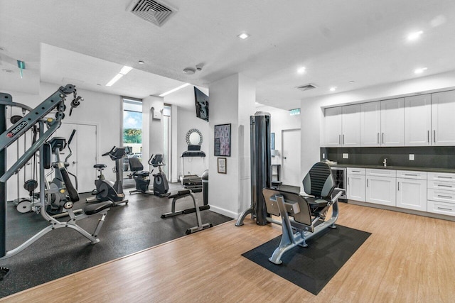 exercise room with light hardwood / wood-style flooring and a textured ceiling