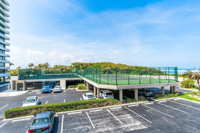 view of parking / parking lot featuring a water view and tennis court