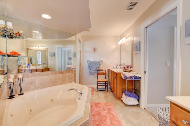 bathroom featuring tile patterned flooring, vanity, and tiled bath