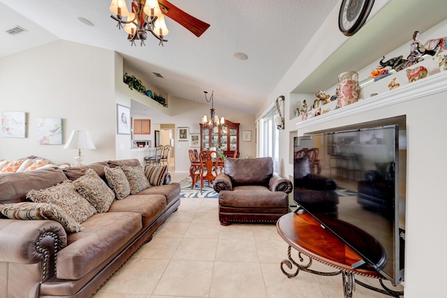 living room featuring ceiling fan with notable chandelier, light tile patterned floors, and vaulted ceiling