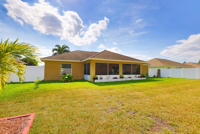 back of property featuring a sunroom and a lawn