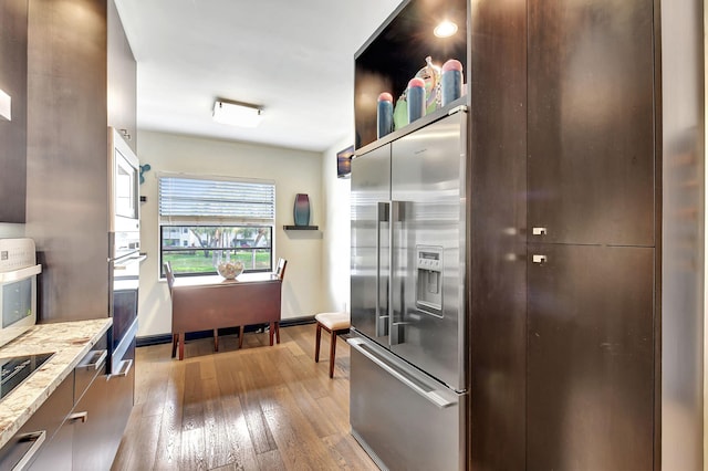 kitchen featuring appliances with stainless steel finishes, light stone counters, and wood-type flooring