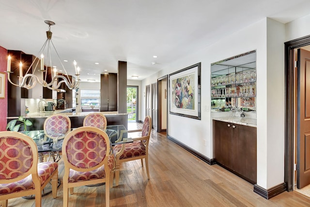 dining space with light hardwood / wood-style floors, sink, and a chandelier