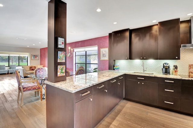 kitchen featuring kitchen peninsula, light stone counters, light hardwood / wood-style flooring, and a healthy amount of sunlight