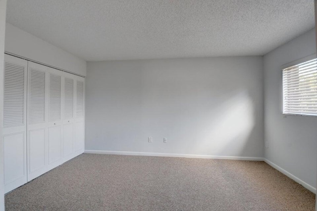 unfurnished bedroom featuring carpet, a textured ceiling, and a closet