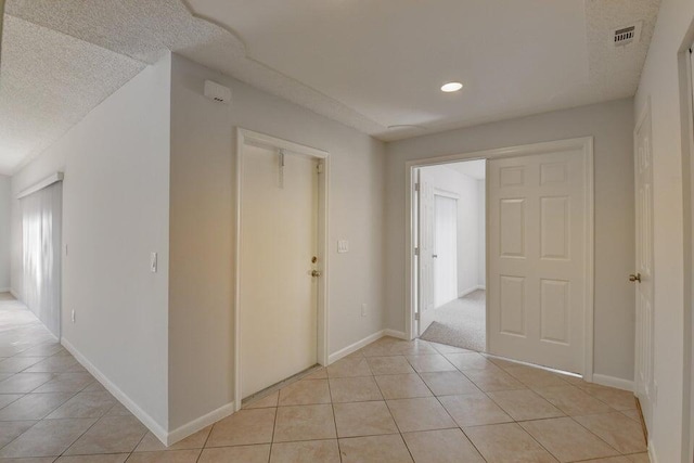 corridor with light tile patterned floors and a textured ceiling