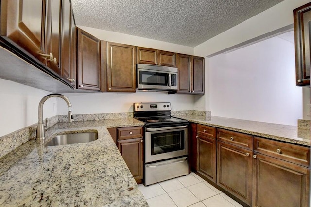 kitchen featuring light stone counters, sink, a textured ceiling, and appliances with stainless steel finishes