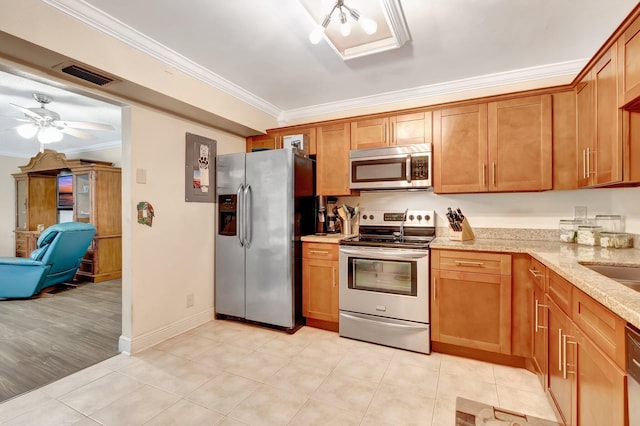 kitchen featuring ceiling fan, ornamental molding, light tile patterned floors, appliances with stainless steel finishes, and light stone counters