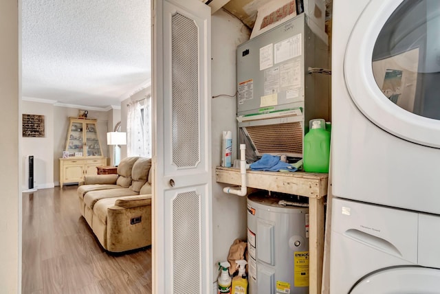 interior space with water heater, crown molding, stacked washer and dryer, wood-type flooring, and a textured ceiling