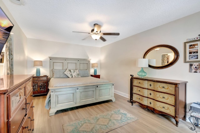 bedroom with ceiling fan, light hardwood / wood-style flooring, and a textured ceiling