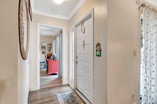 entrance foyer with a textured ceiling, light hardwood / wood-style floors, and ornamental molding