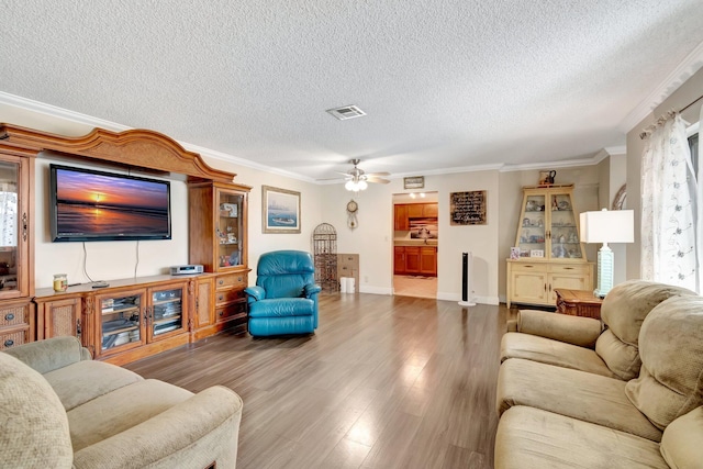 living room with a textured ceiling, ceiling fan, wood-type flooring, and crown molding