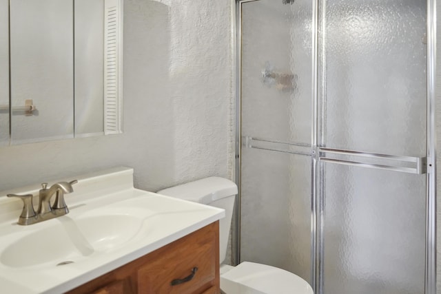 bathroom with toilet, vanity, and an enclosed shower