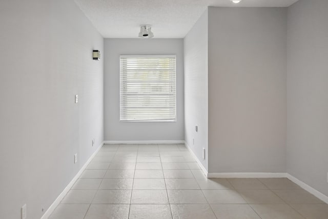 tiled empty room featuring a textured ceiling