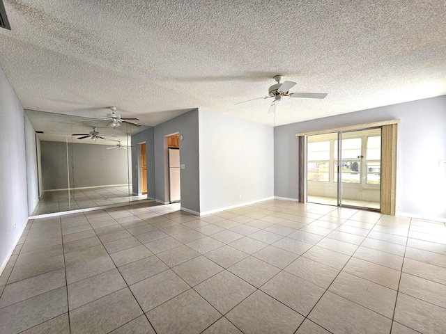 empty room with a textured ceiling, ceiling fan, and light tile patterned floors