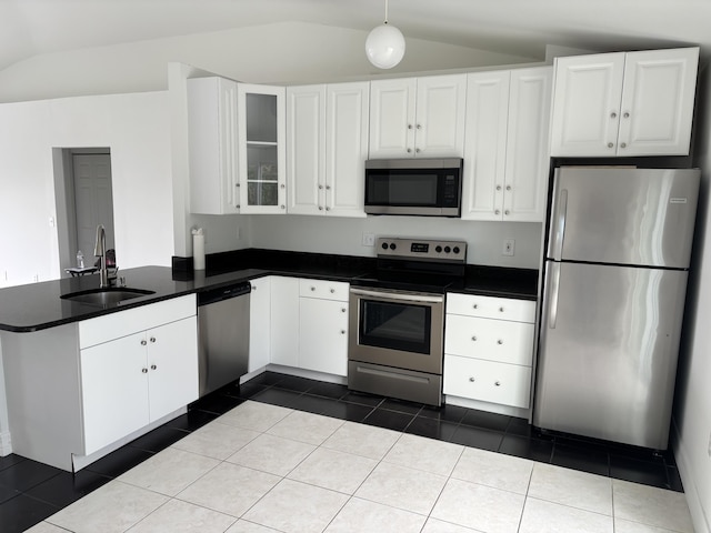 kitchen featuring white cabinets, dark countertops, a peninsula, stainless steel appliances, and a sink