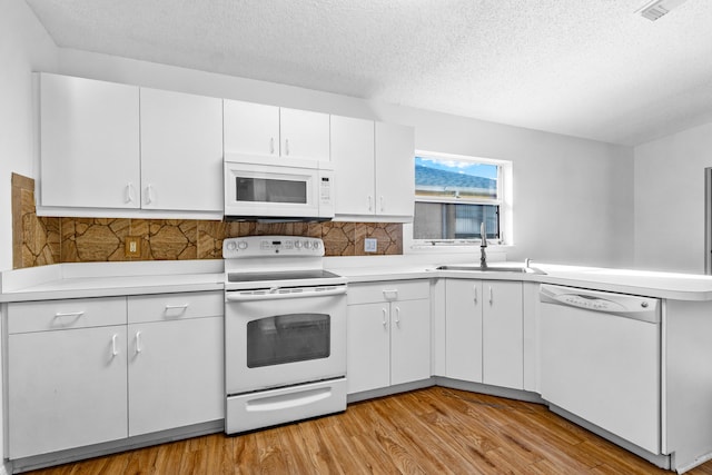 kitchen featuring white cabinets, light wood-type flooring, white appliances, and a textured ceiling