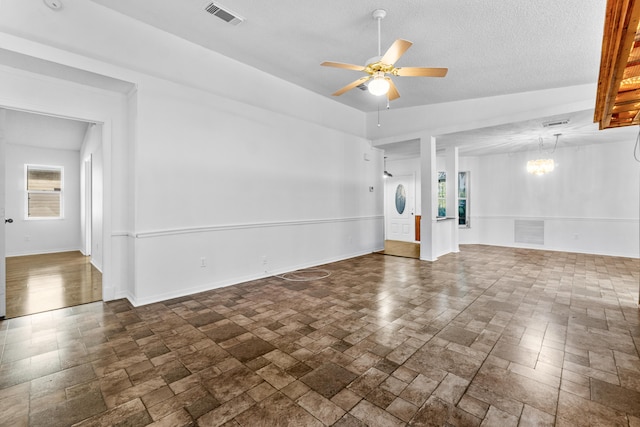 empty room with a textured ceiling and ceiling fan with notable chandelier