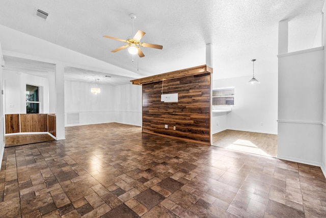 unfurnished living room with ceiling fan with notable chandelier, lofted ceiling, and a textured ceiling