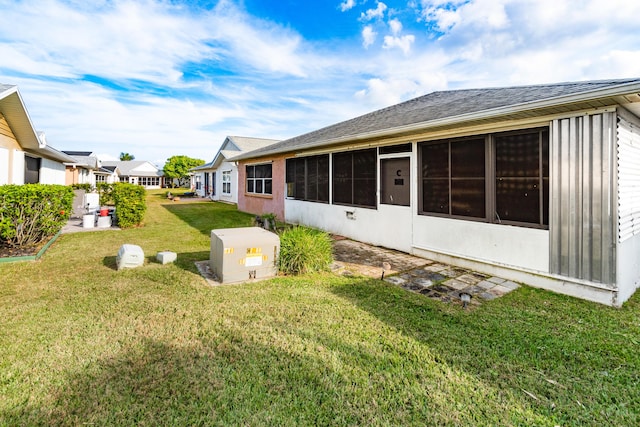 back of house with a lawn and a sunroom