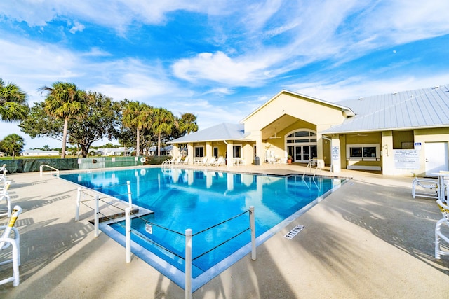 community pool with a patio area and fence