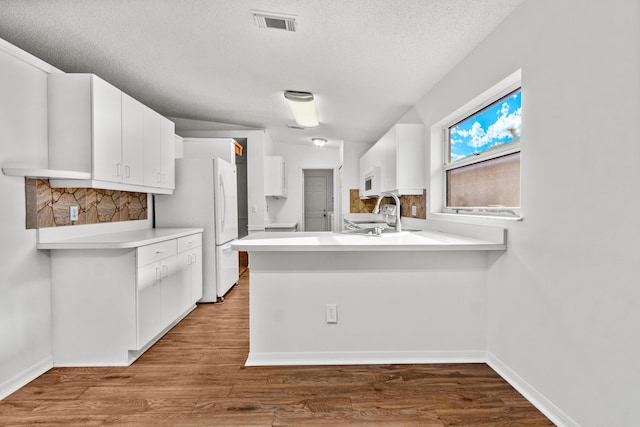 kitchen featuring white cabinetry, sink, kitchen peninsula, wood-type flooring, and lofted ceiling