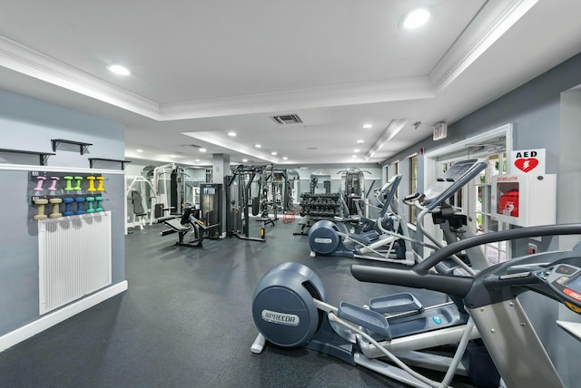 exercise room featuring a raised ceiling and ornamental molding