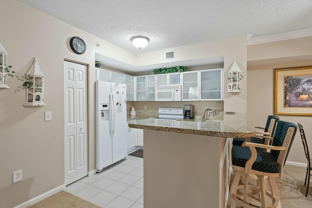 kitchen with kitchen peninsula, a textured ceiling, white appliances, a breakfast bar area, and white cabinets