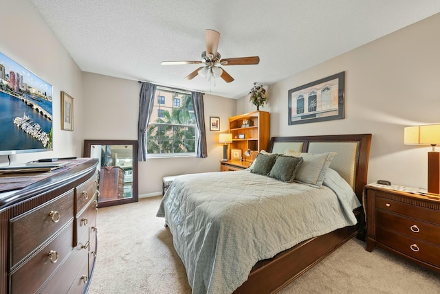 carpeted bedroom with ceiling fan and a textured ceiling